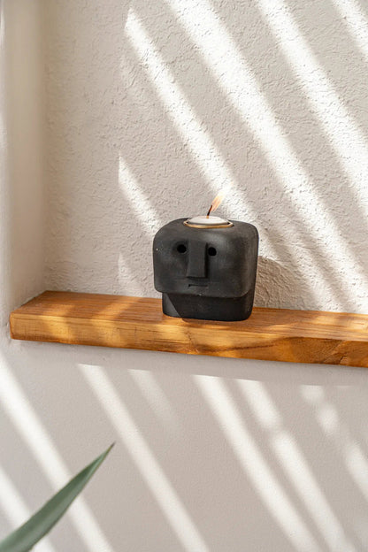 De Sumba Stone #26 kaarsenhouder, zwarte stenen figurine met gezicht, op houten plank