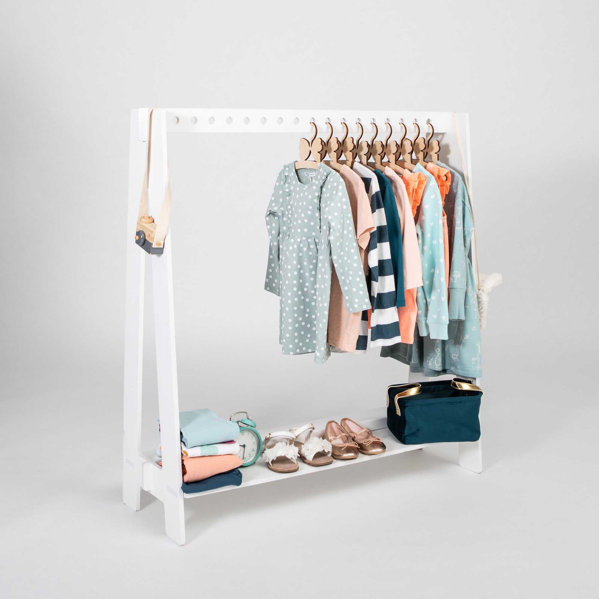 Montessori kledingrek van Sweet Home From Wood, witte houten rek met pastel kleding aan hangers en schoenen onderaan.